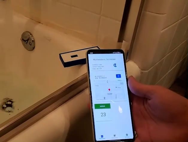 Ultrasonic sensor mounted on a bathtub wall with the app open beside it