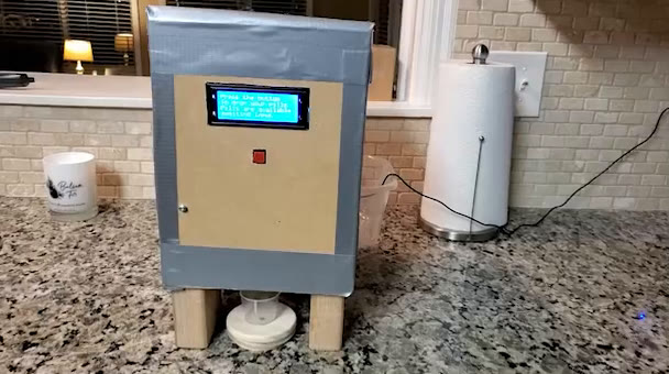 Pill dispenser with an LCD screen and a red button on a kitchen counter
